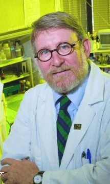 Scientist in a lab coat and glasses working in a laboratory.